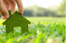 a man's hand holding the shape of a house out of leaves on grass