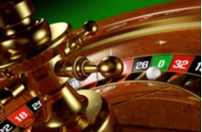 Close up of a standard roulette wheel against a green background with the ball on the green zero pocket
