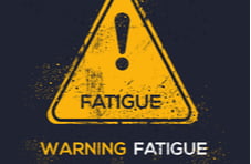 An illustration of a yellow triangle warning sign with the word fatigue and fatigue warning underneath it on a black background
