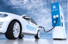 A photo of a white car with ‘Zero Emissions H2’ blue branding filling up at a H2 Hydrogen pump against a cloudy blue sky
