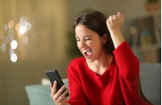 woman wearing a red sweater very happy because she just won playing video poker on her phone