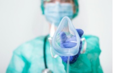 A woman in surgical kit holding an oxygen mask