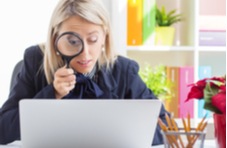 woman looking at her laptop screen through a magnifying glass to get all the info on the best slots