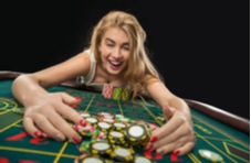 a woman pulling casino chips she's just won playing roulette